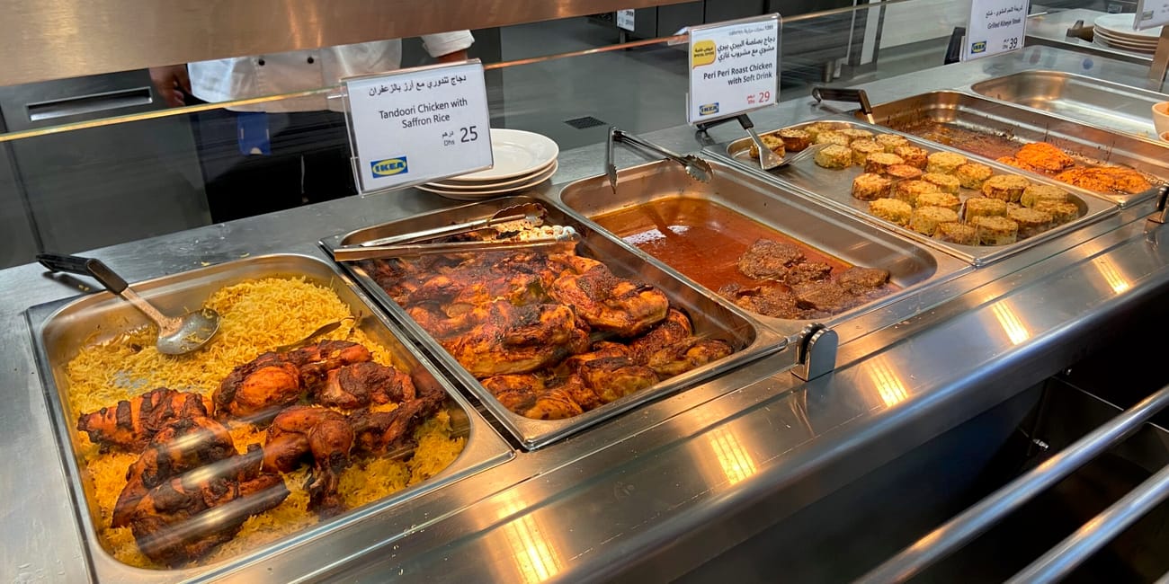 Bufet z daniami z kurczaka w dubai foods, uae, z etykietami potraw i ryżem biryani.