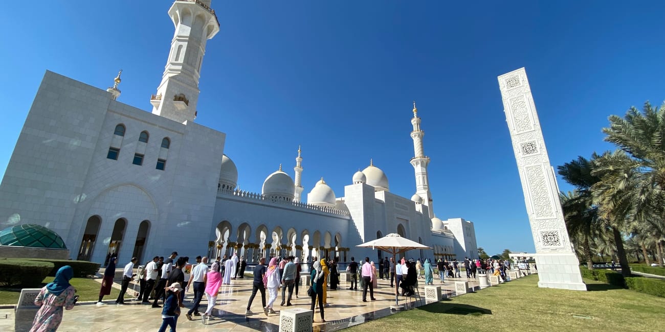 Wielki biały meczet w abu zabi z minaretami i zwiedzającymi na dziedzińcu
