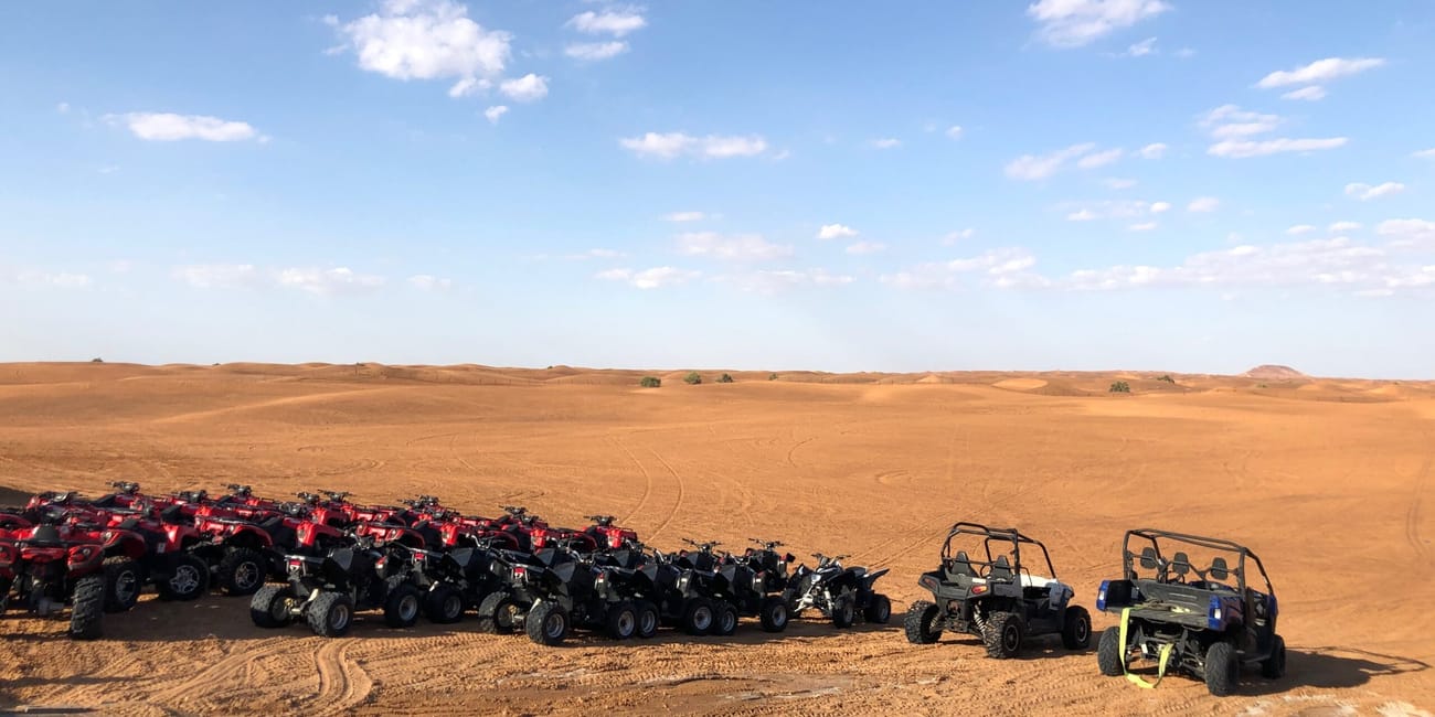 Dubai safari: rząd quadów i buggy na pustynnym terenie pod błękitnym niebem
