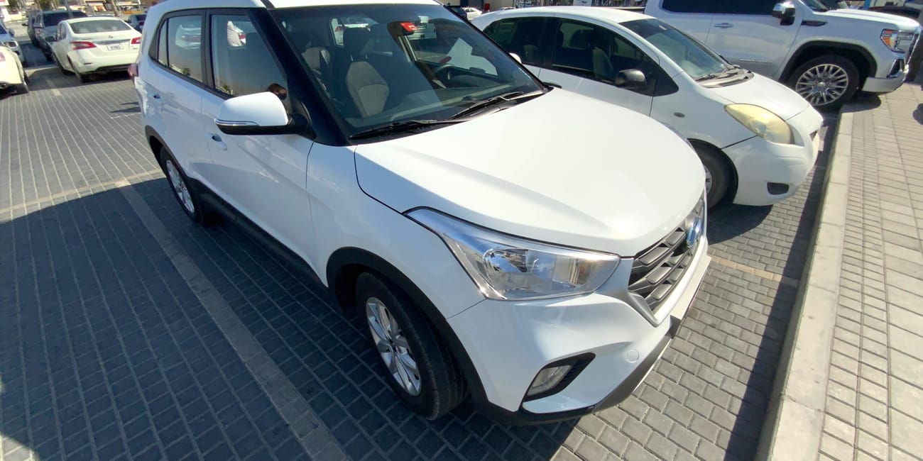 Białe samochody wypożyczone w dubai rental car, zaparkowane na placu w dubaju.