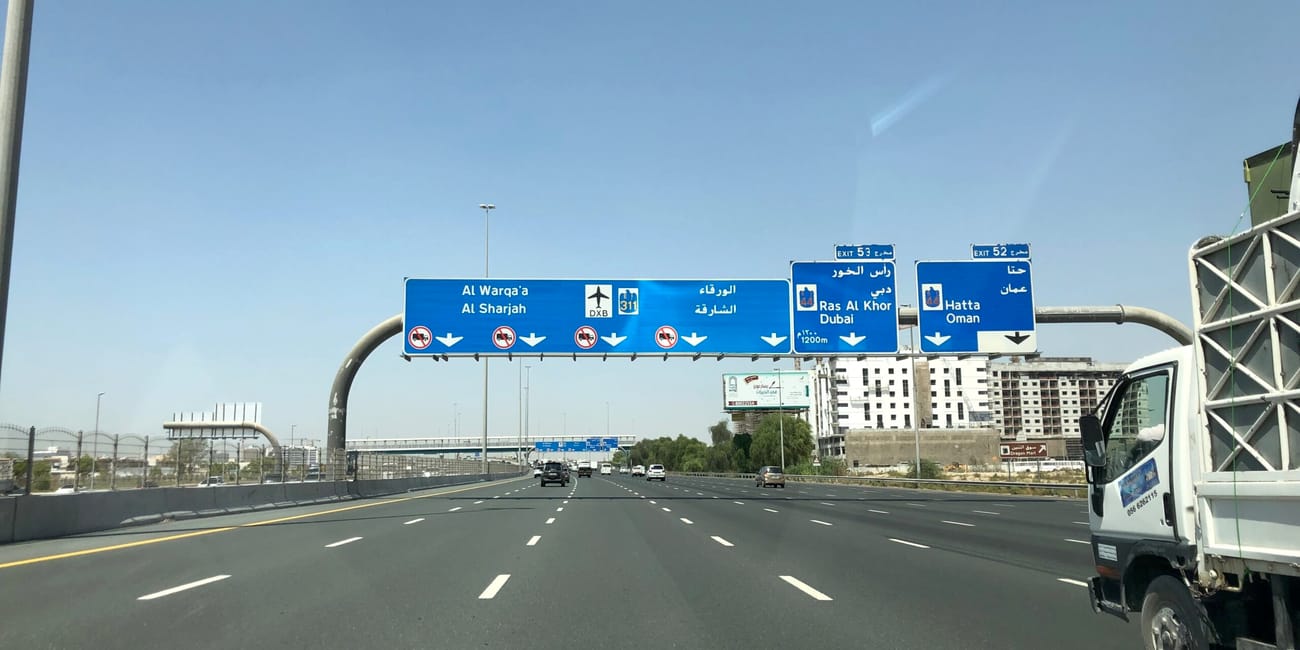 Autostrada w dubaju z niebieskimi znakami kierunku na ras al khor i hatta, widziana z samochodu