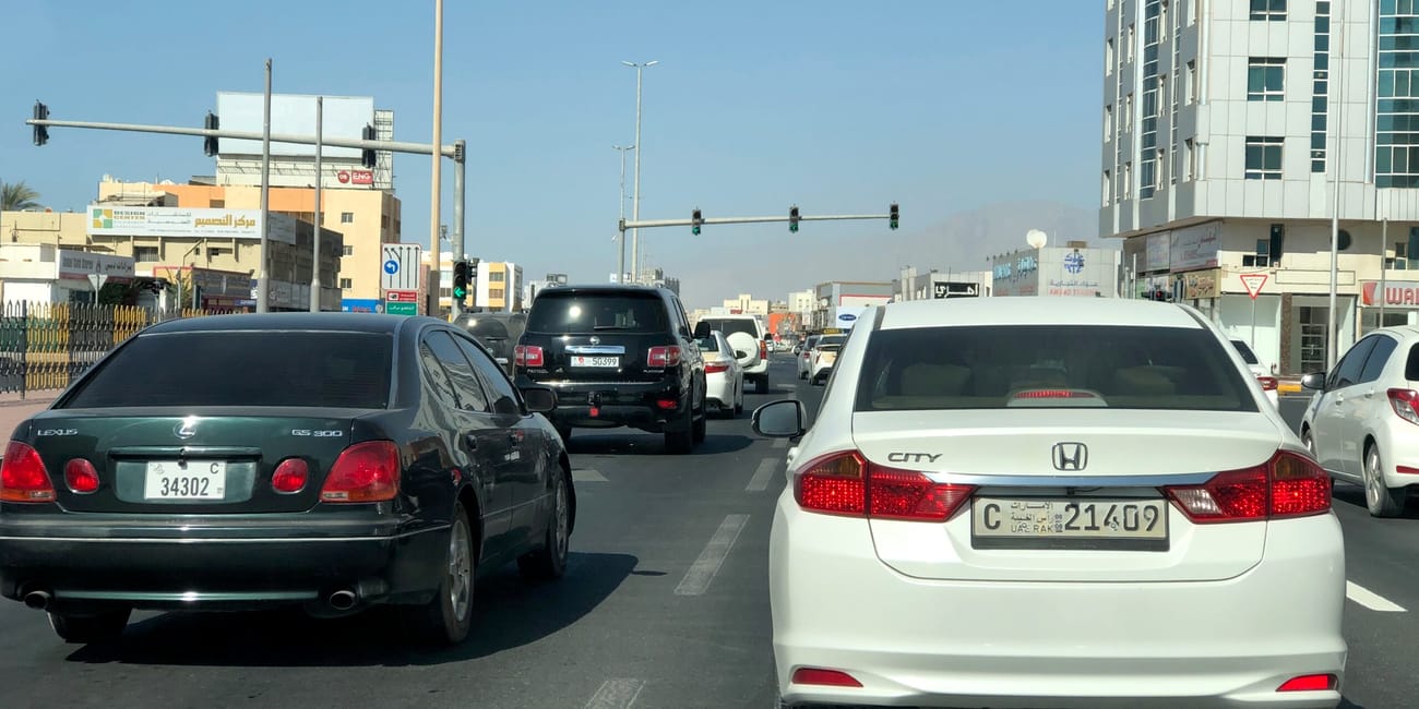 Ulica w ras al khaimah z ruchem samochodowym i wysokimi budynkami po obu stronach.