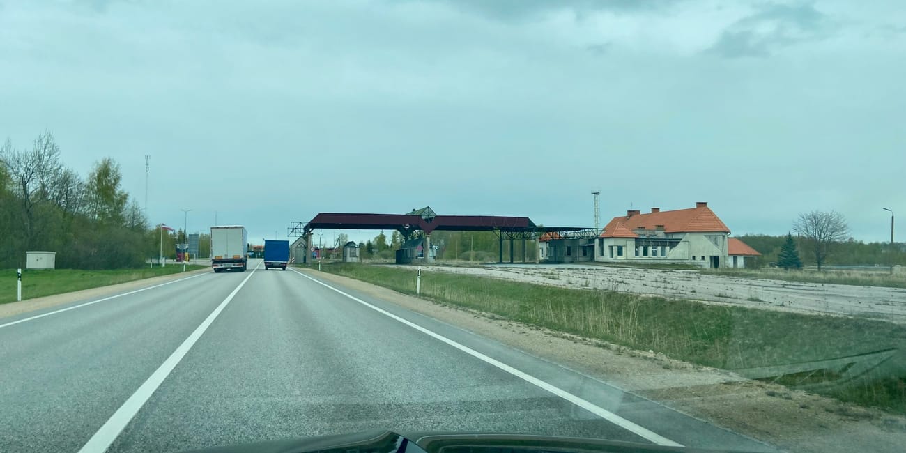 Road view in tallinn, estonia, with a rail crossing and buildings under a cloudy sky