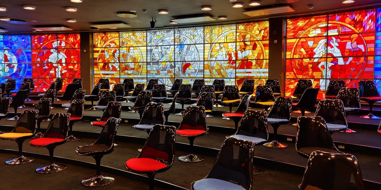 Tallinn conference room with colorful stained-glass mural and rows of modern chairs and tables