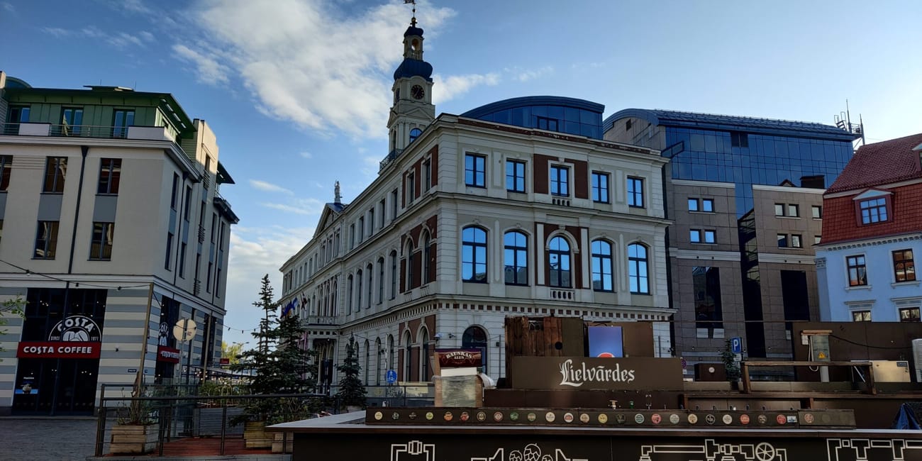 Ryga, stare miasto: zabytkowa kamienica z wieżą i nowoczesne budynki na tle nieba