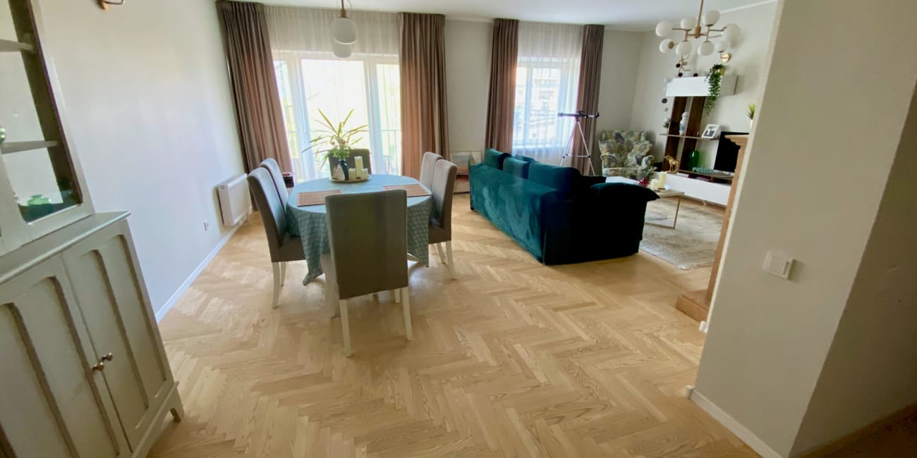 Salon i jadalnia w mieszkaniu w wilnie z niebieską sofą i dużymi oknami