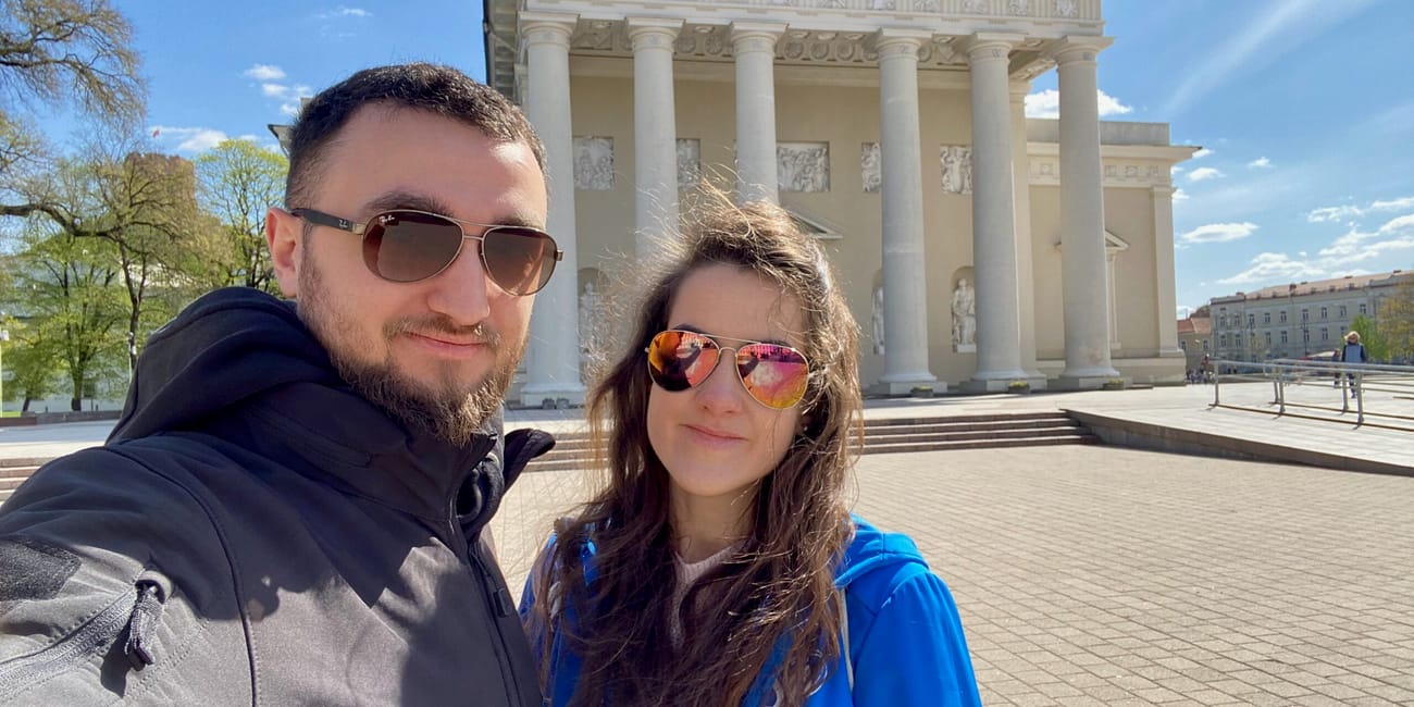 Selfie dwojga osób przed katedrą w wilnie, z białą kolumnadą w tle