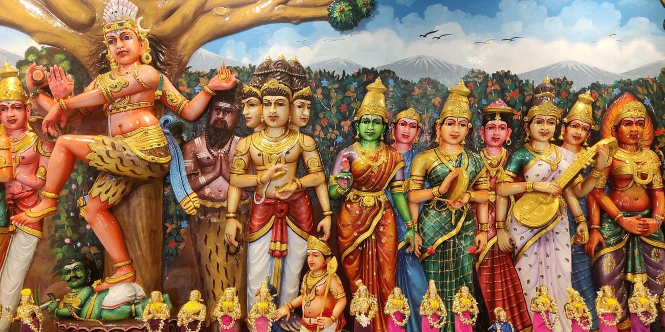 Kolorowe posągi hinduskich bóstw w kuala lumpur, z dużą figurą pod drzewem w tle