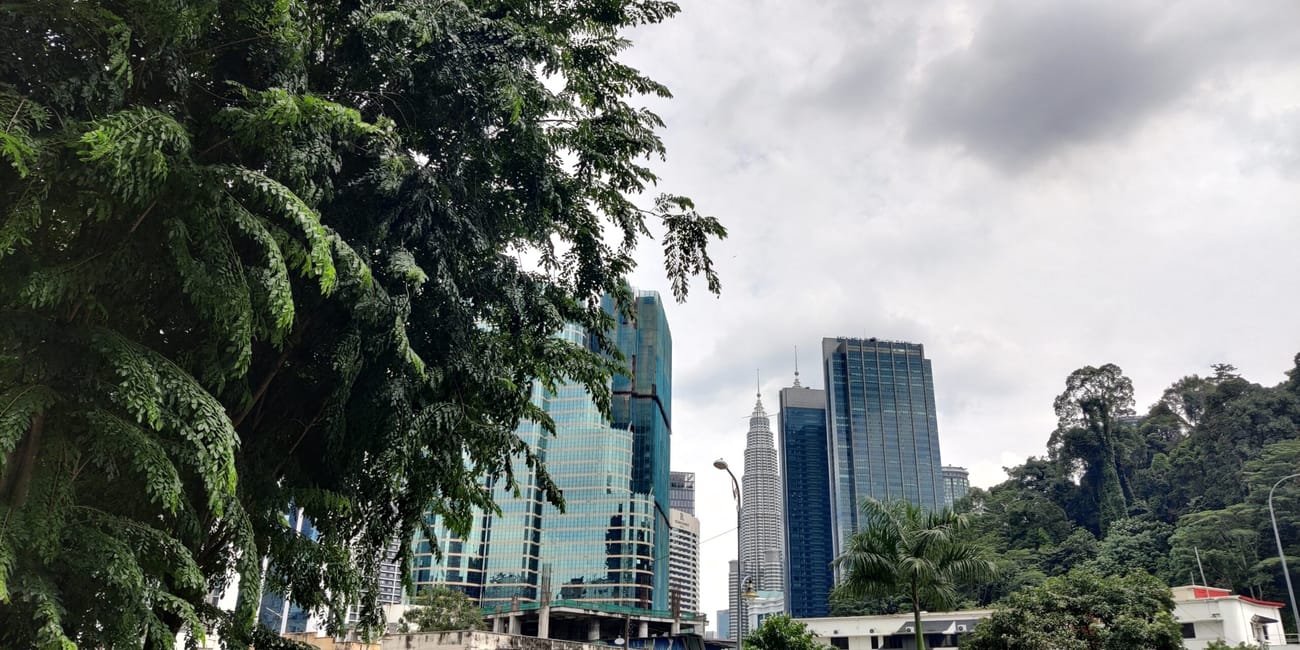 Panorama kuala lumpur z wieżowcem petronas towers w tle i bujną zielenią na pierwszym planie