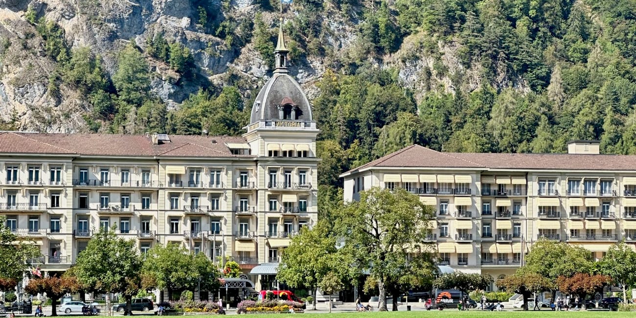 Hotel victoria jungfrau w interlaken na tle górskiego zbocza i zielonego parku