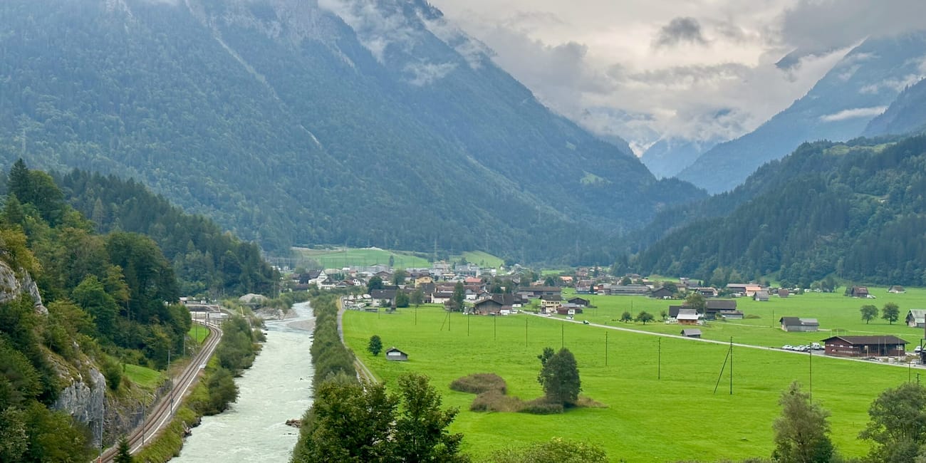 Aaerschlucht w szwajcarii: dolina z rzeką, zielonymi łąkami i górami spowitymi chmurami