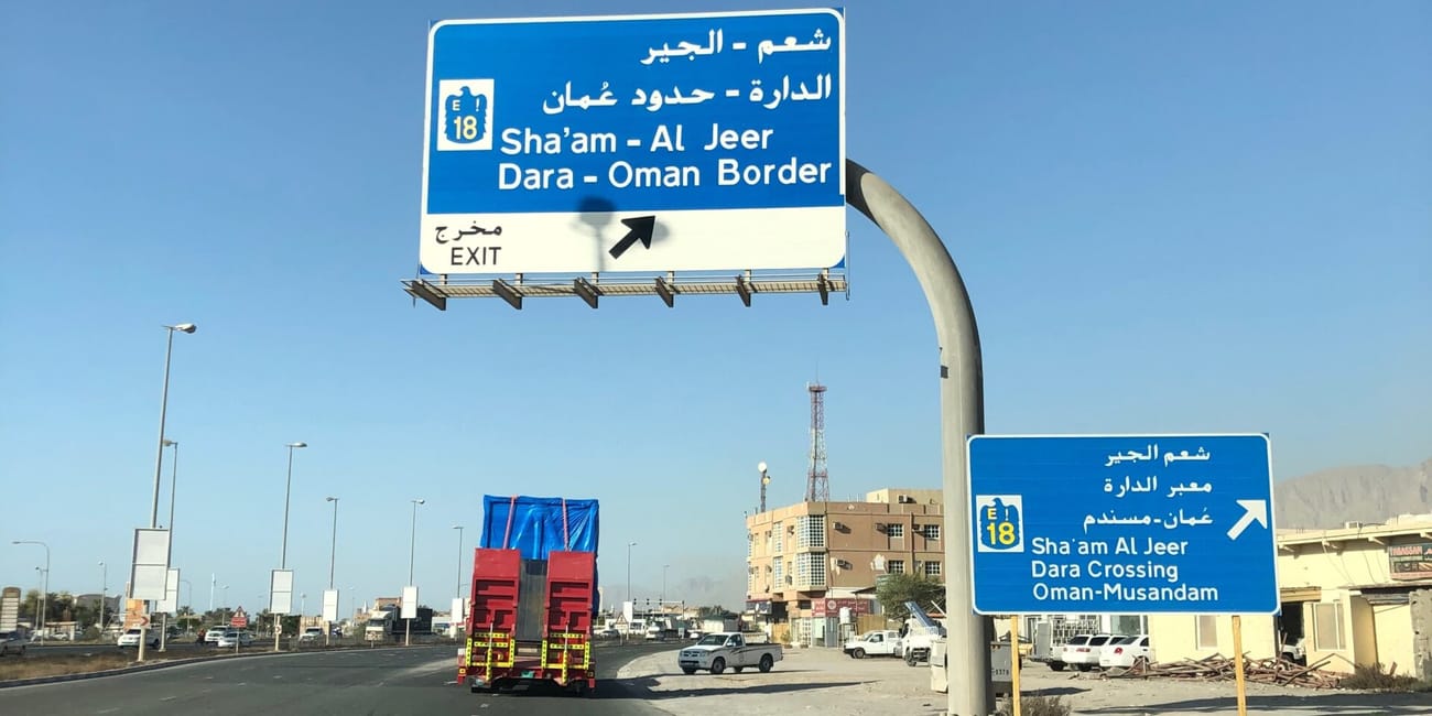 Droga w ras al khaimah z niebieskimi znakami kierującymi do sha’am al jeer, dara i granicy z omanem
