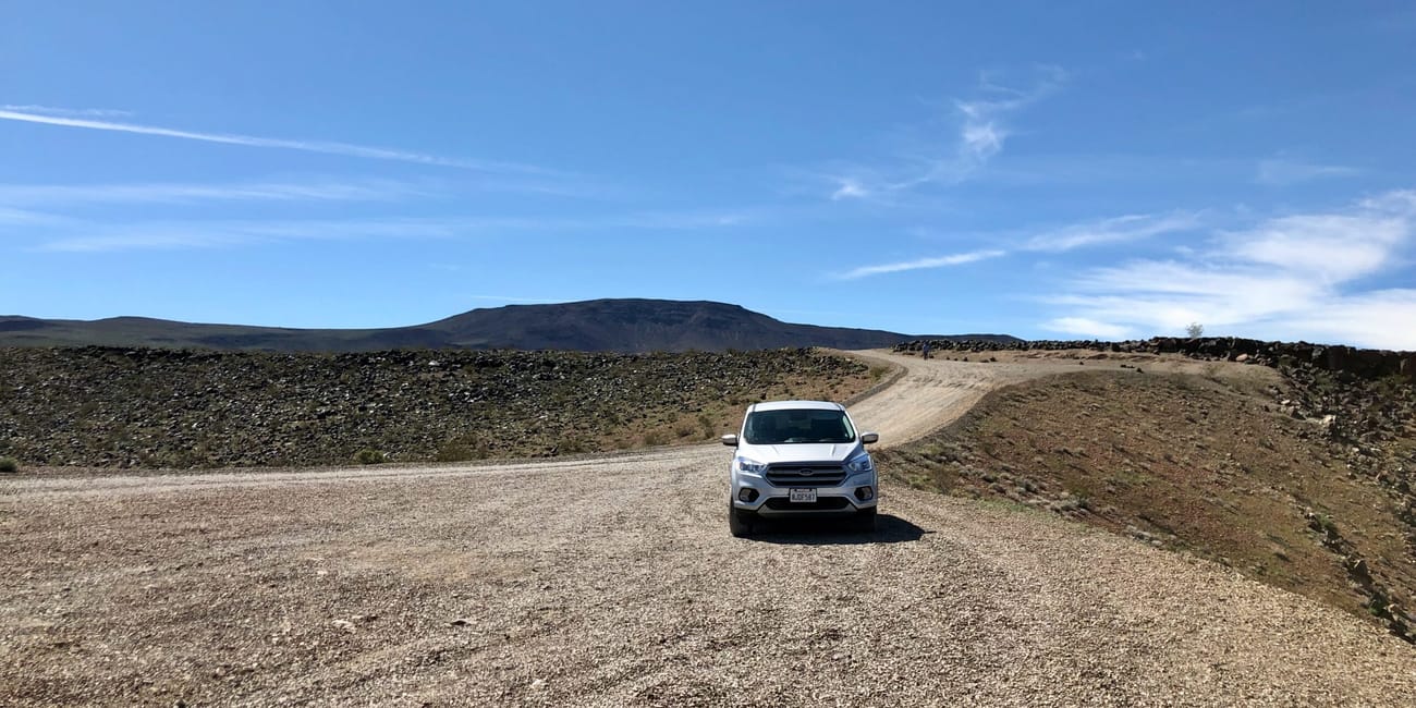 Death valley car w usa: biały samochód na żwirowej drodze w pustynnym krajobrazie.
