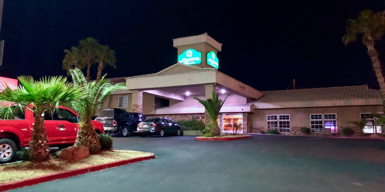 Nocny widok budynku przy ulicy w las vegas z zaparkowanymi samochodami i palmami.