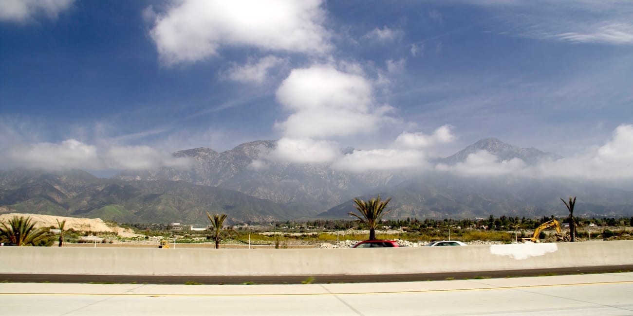 Autostrada w los angeles z górami w tle i palmami przy drodze