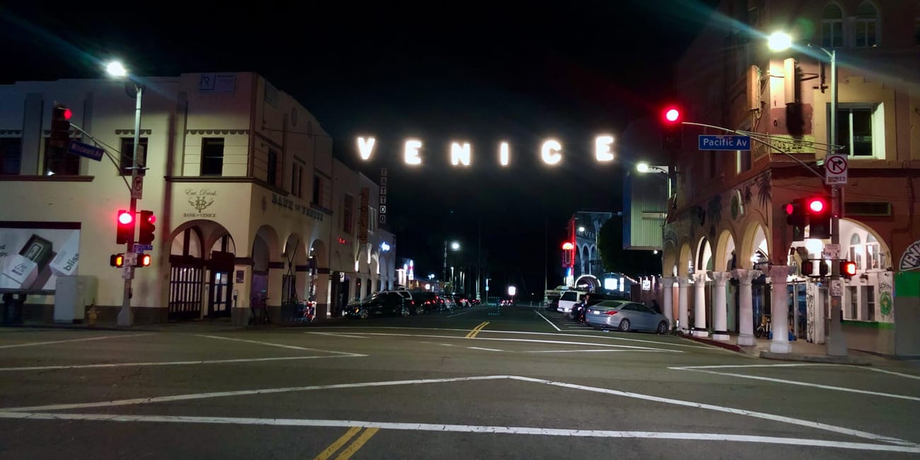 Nocny widok na venice w los angeles z podświetlonym napisem nad ulicą.