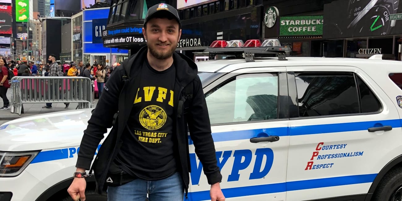Mężczyzna stoi przed radiowozem nypd na times square w nowym jorku, trzymając torby na zakupy.