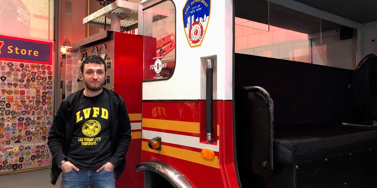 Mężczyzna stoi obok ekspozycji wozu strażackiego fdny w new york city.