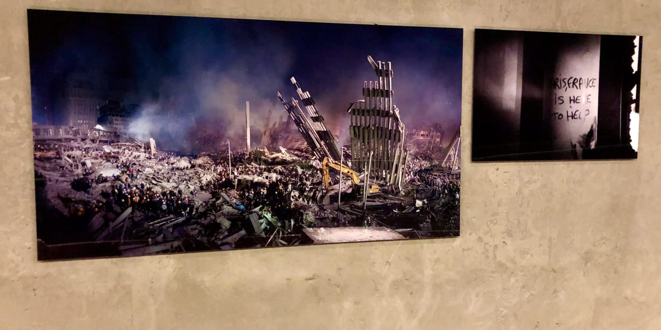 Nowojorskie 9/11 museum z fotografiami ruin po zamachu i napisem na ścianie