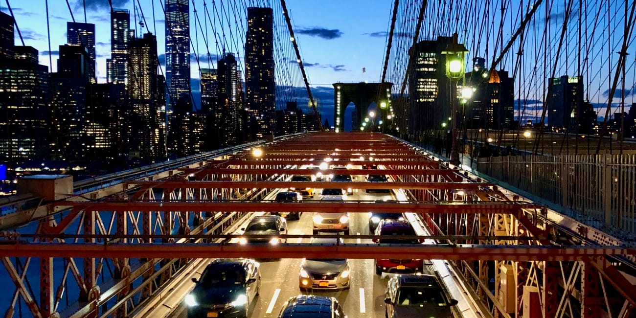 Most brooklyński w nowym jorku nocą, z ruchem samochodów i panoramą manhattanu.