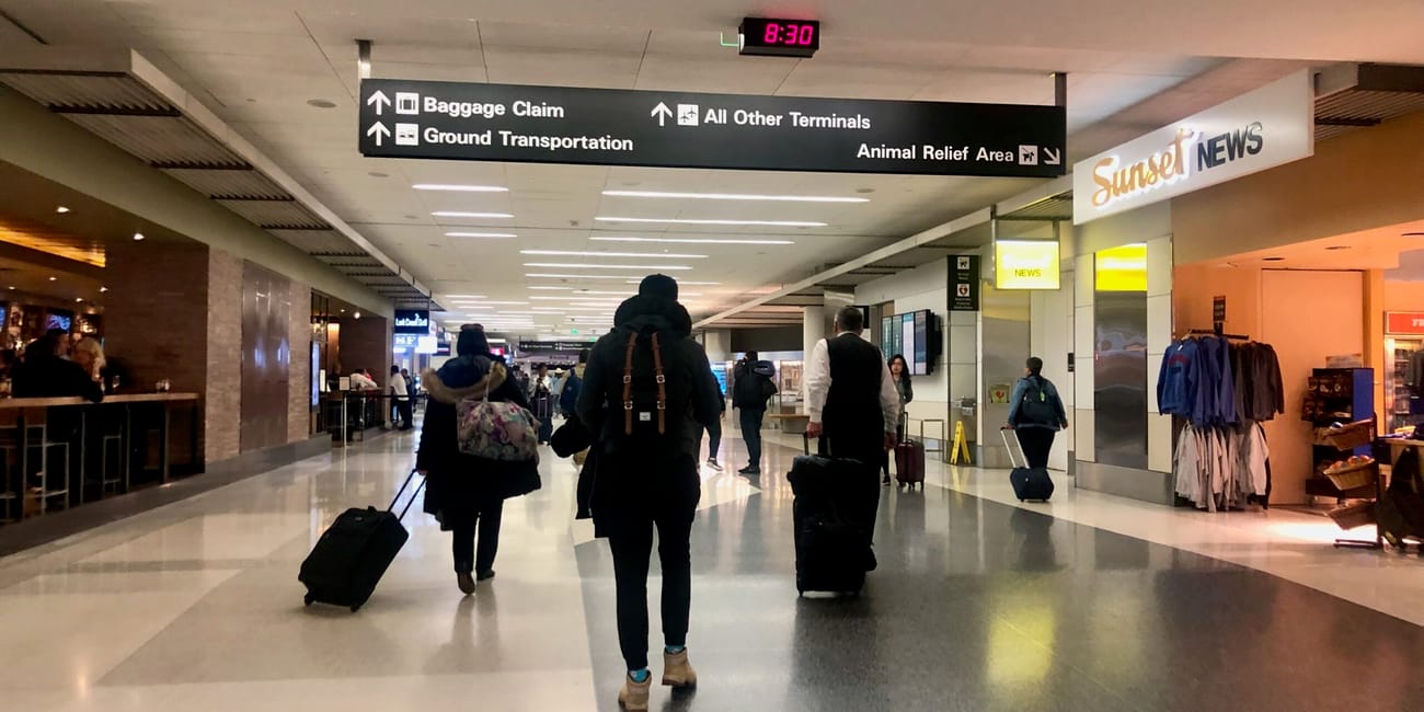 San francisco airport: pasażerowie idą w hali przylotów pod znakami kierunkowymi.