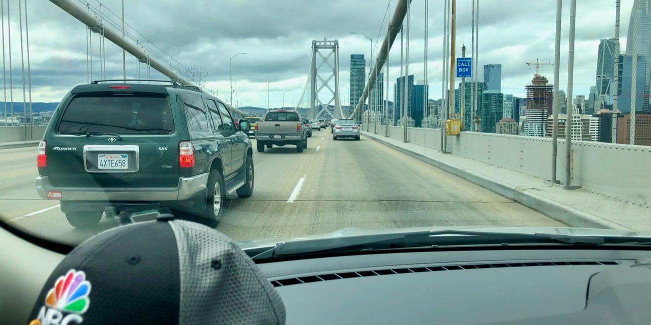 Widok z samochodu na bay bridge w san francisco z ruchem i panoramą miasta na tle chmur