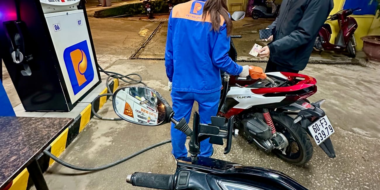Stacja paliw w da lat, nocą, z tankowaniem skutera przez pracownicę.