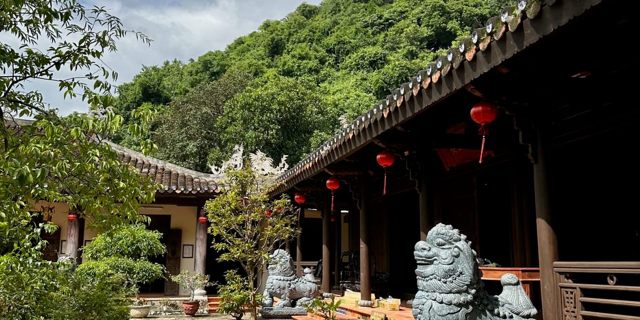 Świątynia w marble mountains w da nang z kamiennymi lwami i czerwonymi lampionami na tle zielonego wzgórza.