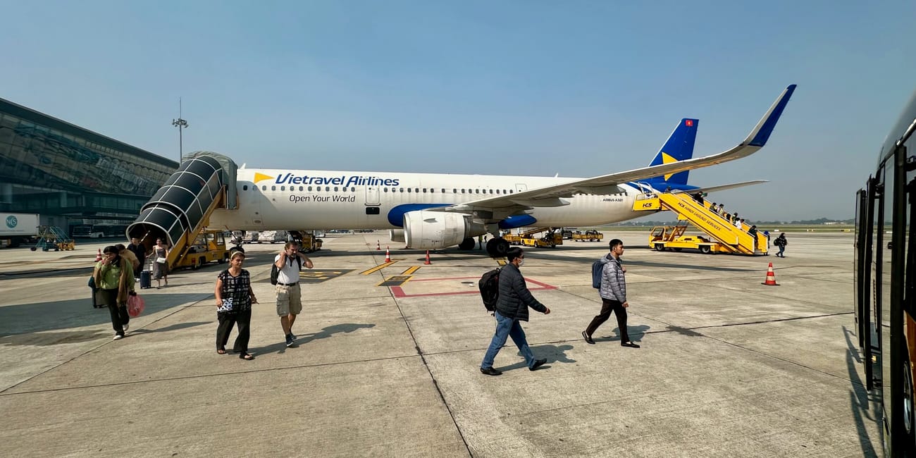 Pasażerowie idą po płycie lotniska do samolotu vietravel airlines w hanoi, wietnam.