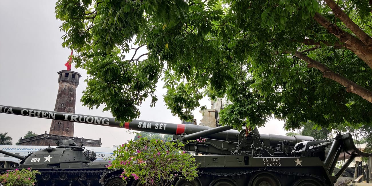 Hanoi flag tower z eksponowanym sprzętem wojskowym pod drzewami