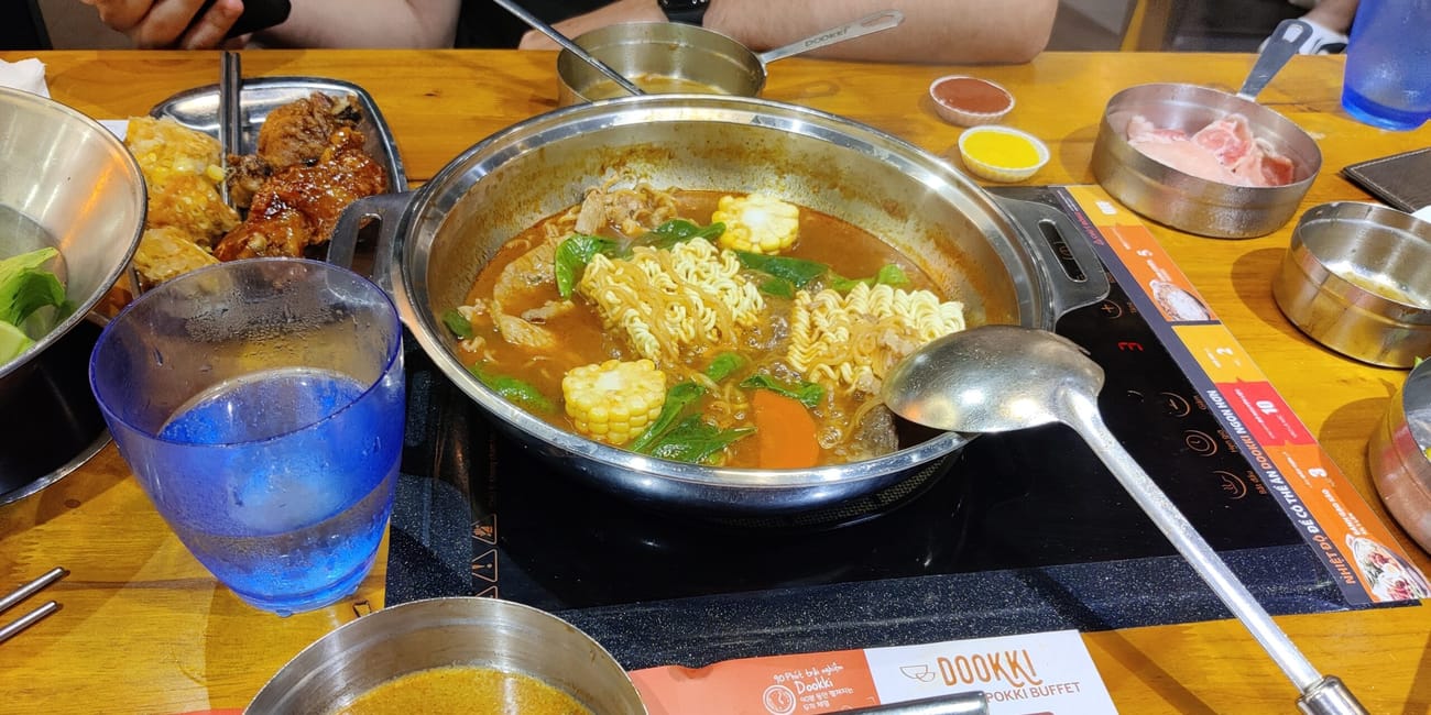 Bufet z gorącym garnkiem w hanoi, vietnam, z makaronem, warzywami i mięsem na stole