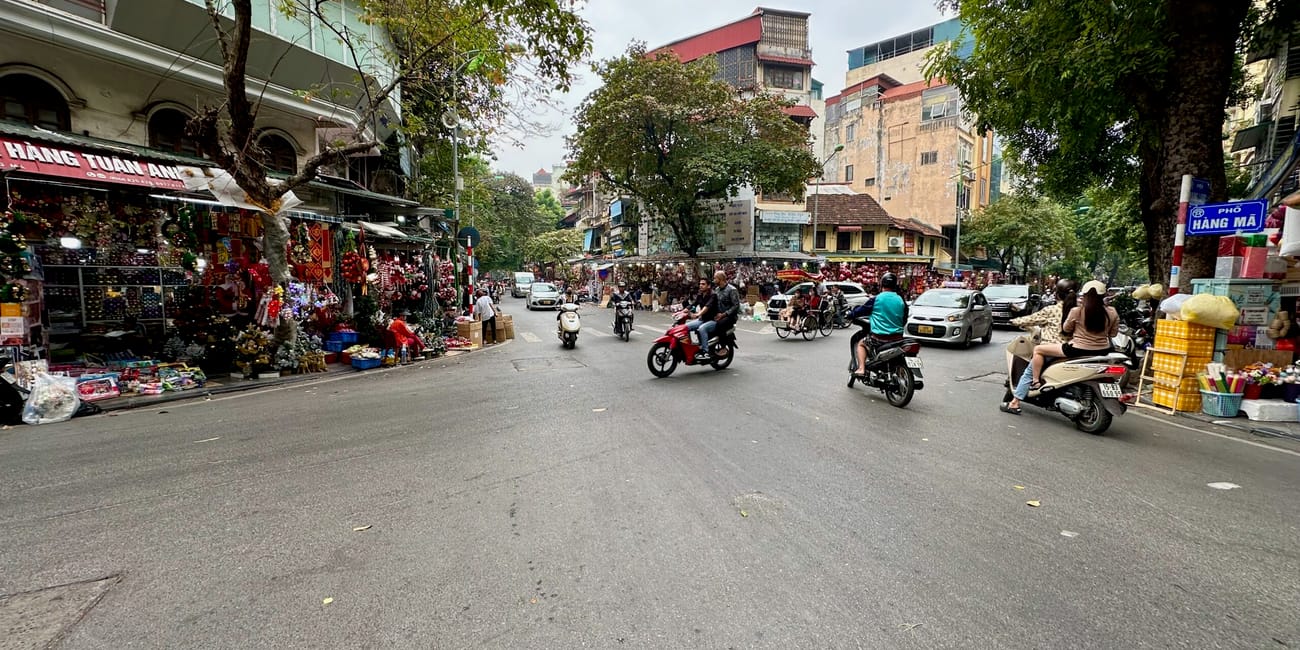 Ulica hàng mã w hanoi z ruchem skuterów i straganami po obu stronach