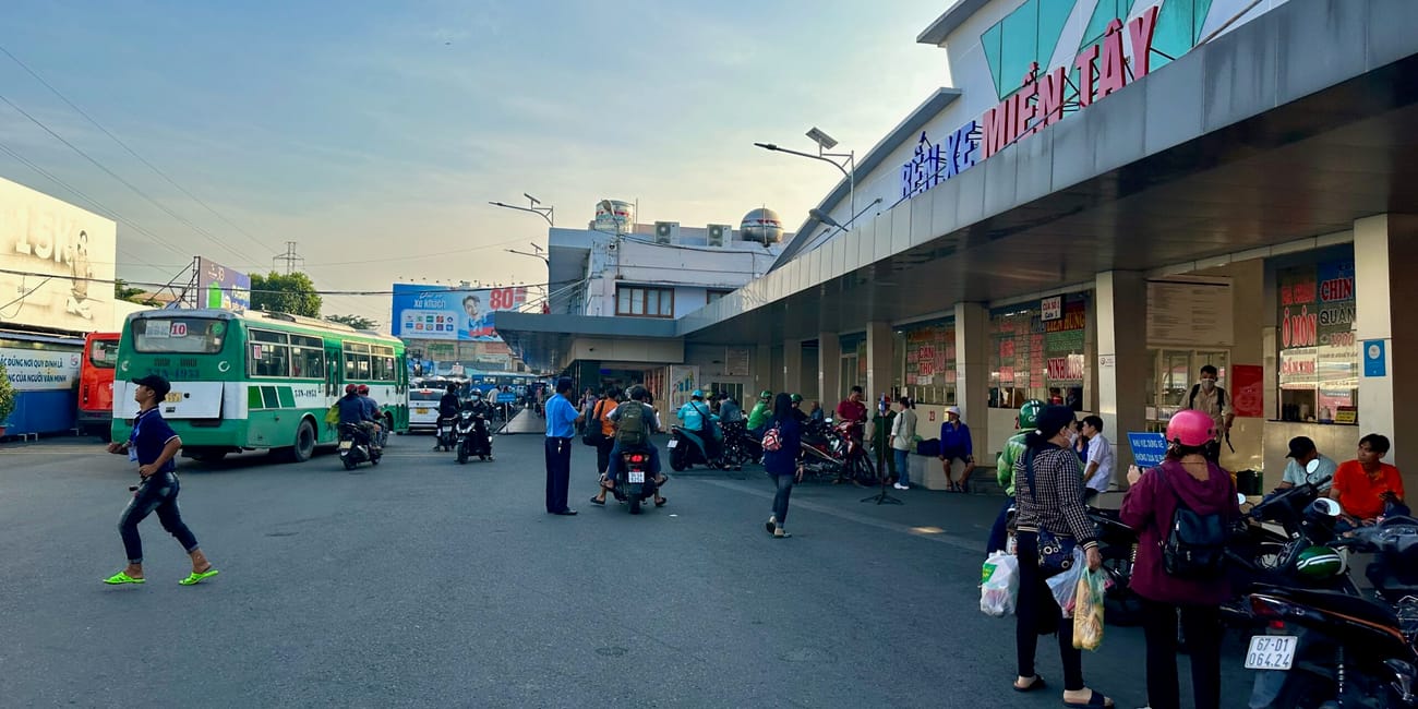 Ruchliwy dworzec autobusowy w ho chi minh z autobusami, skuterami i pasażerami.