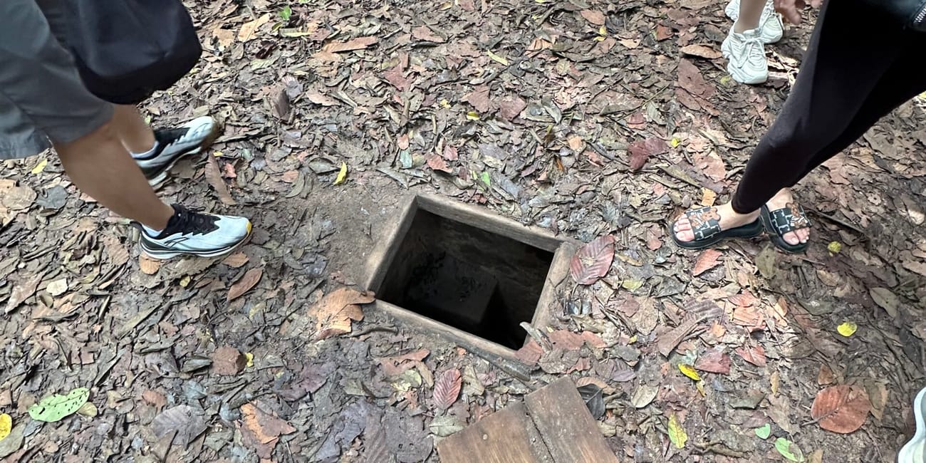 Wejście do tuneli cu chi w ho chi minh, otwarte w ziemi wśród turystów.