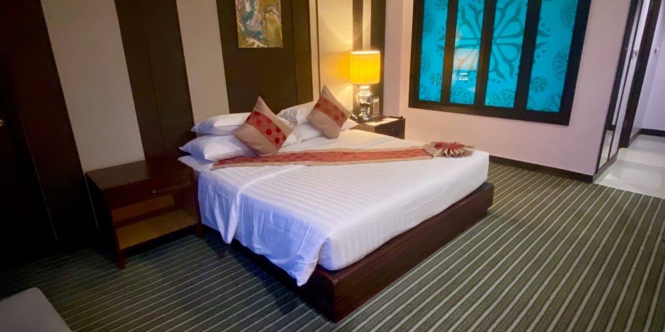 Pokój hotelowy w bangkoku z łóżkiem, lampą i niebieskim oknem