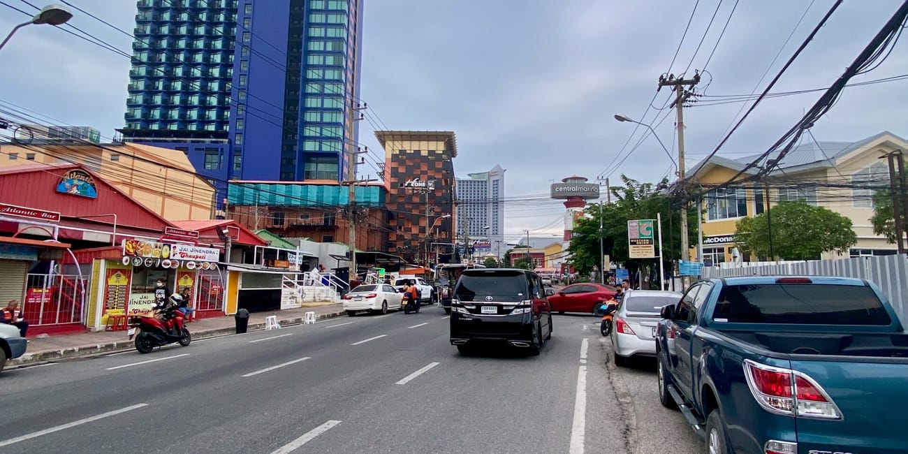 Roadway in pattaya, thailand with parked cars, power lines, and tall buildings including siam @ siam hotel
