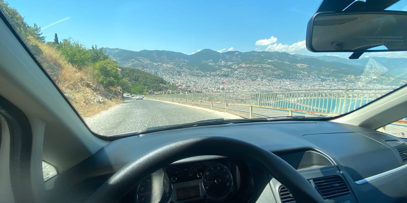 Widok z samochodu na antalya: górska droga nad miastem i morzem w słoneczny dzień