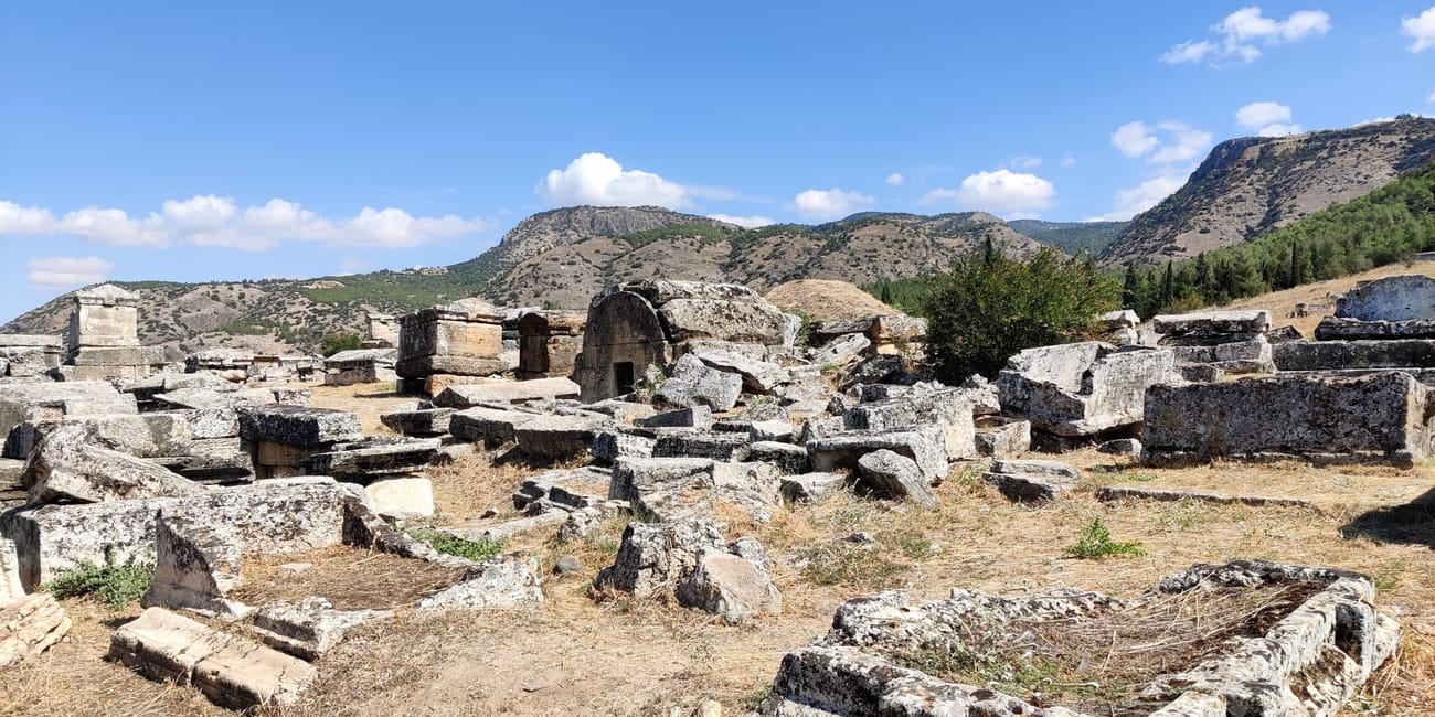Nekropolia hierapolis w pamukkale, kamienne grobowce na tle wzgórz i nieba.