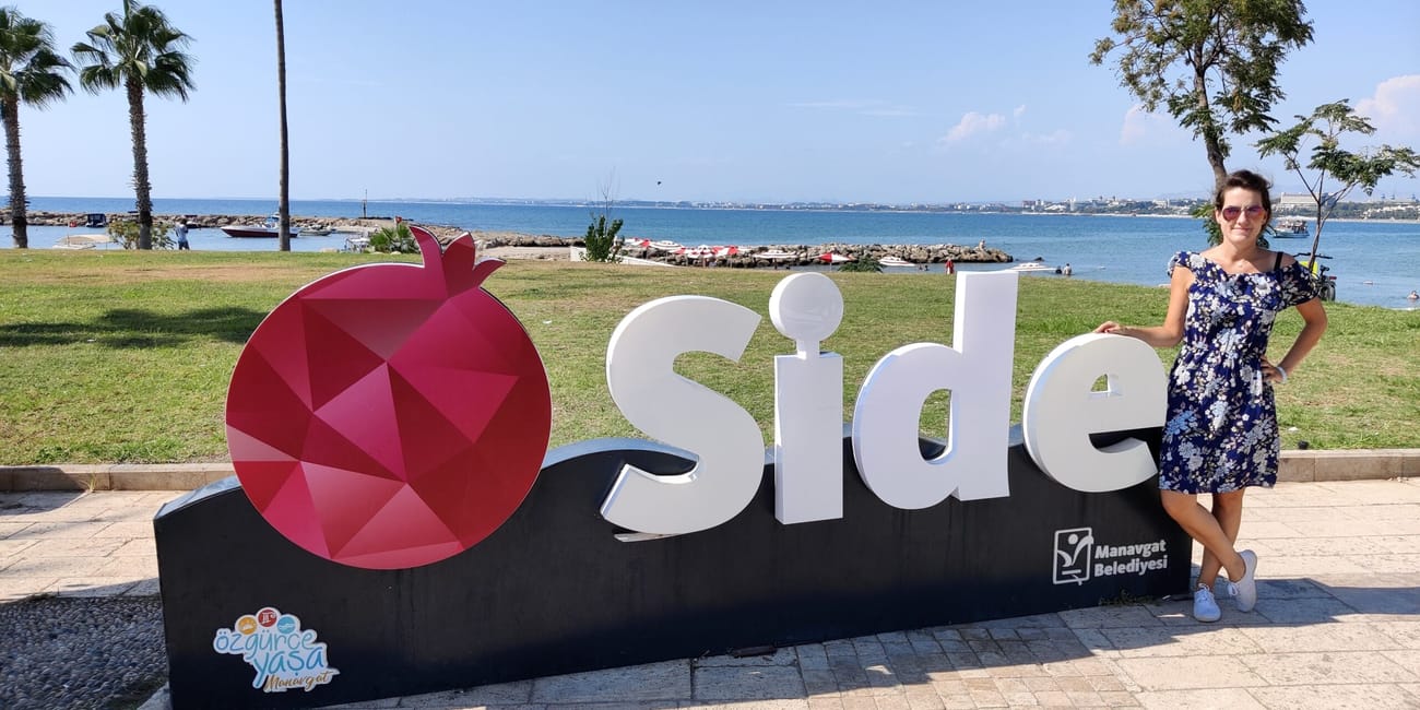 Naprzeciw napisu side nad morzem w turcji stoi kobieta.