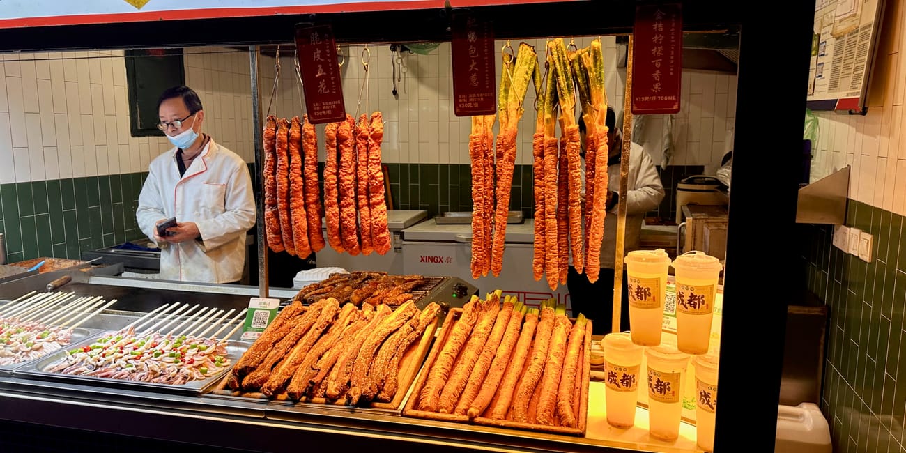 Stoisko z przekąskami na chengdu jinli street w chinach, z wiszącymi smażonymi potrawami.