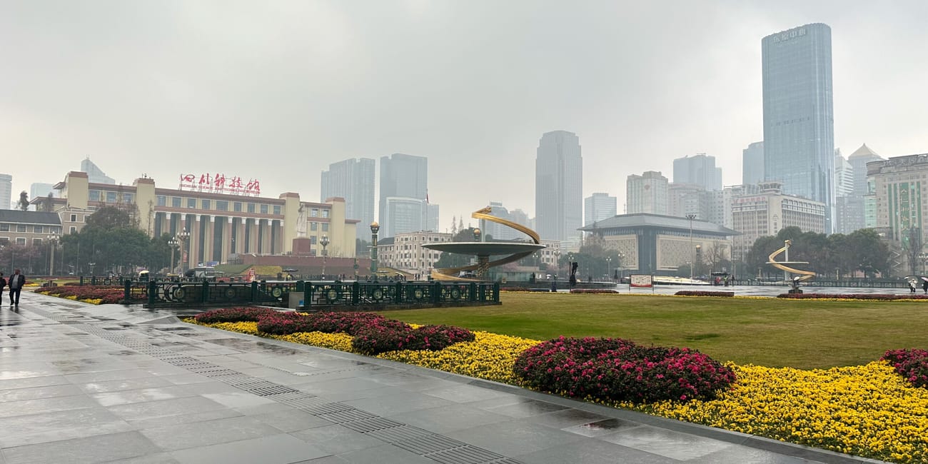Plac tianfu w chengdu z rabatami kwiatów, fontanną i wieżowcami w tle