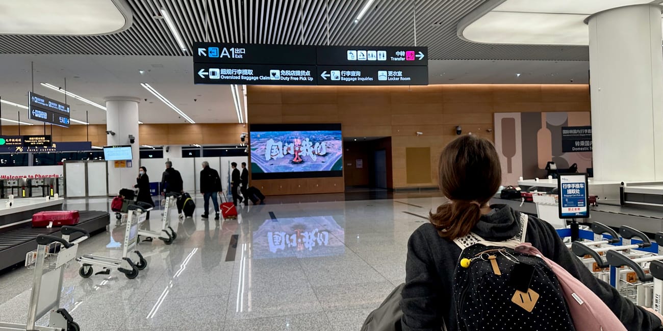 Hala przylotów lotniska w chengdu z podróżnymi i tablicami kierunkowymi
