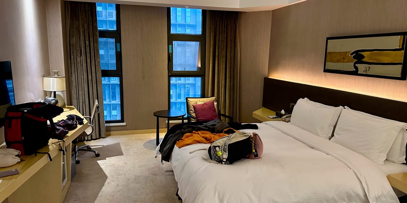 Pokój hotelowy w chengdu z rozłożonym łóżkiem, biurkiem i walizkami.