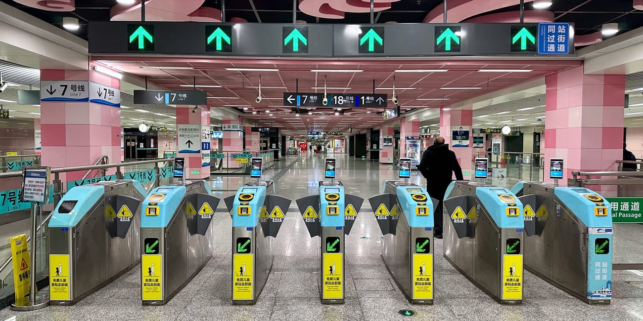 Bramki wejściowe na stacji metra w chengdu z oznaczeniami linii i zielonymi strzałkami.