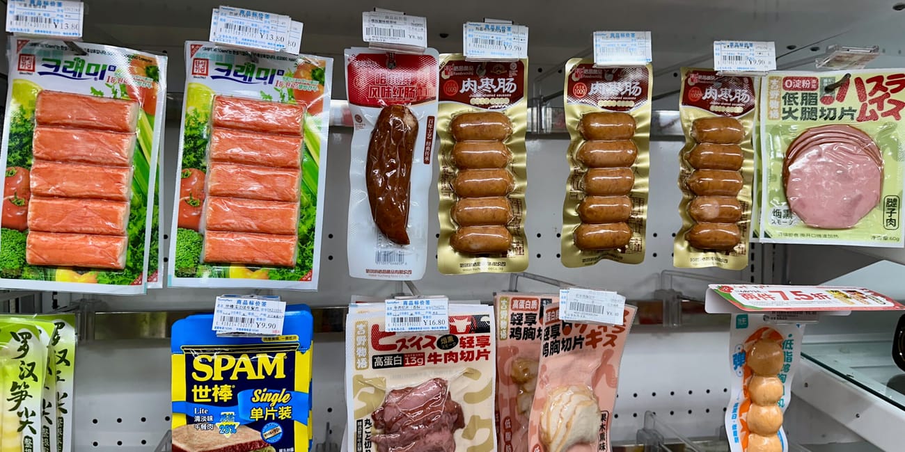 Półka z pakowanymi wyrobami mięsnymi w sklepie w chengdu, z widocznymi cenówkami i opakowaniem spam.
