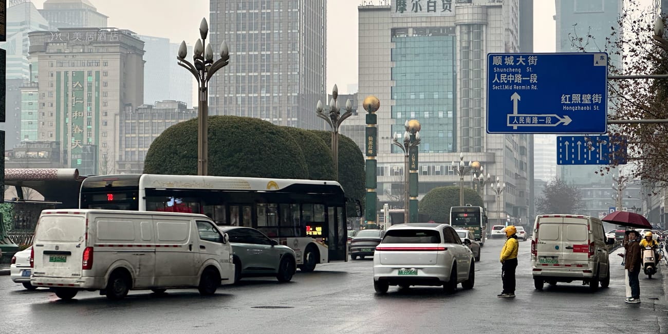 Ulica shuncheng w chengdu z ruchem, autobusami i wieżowcami w deszczowej mgle