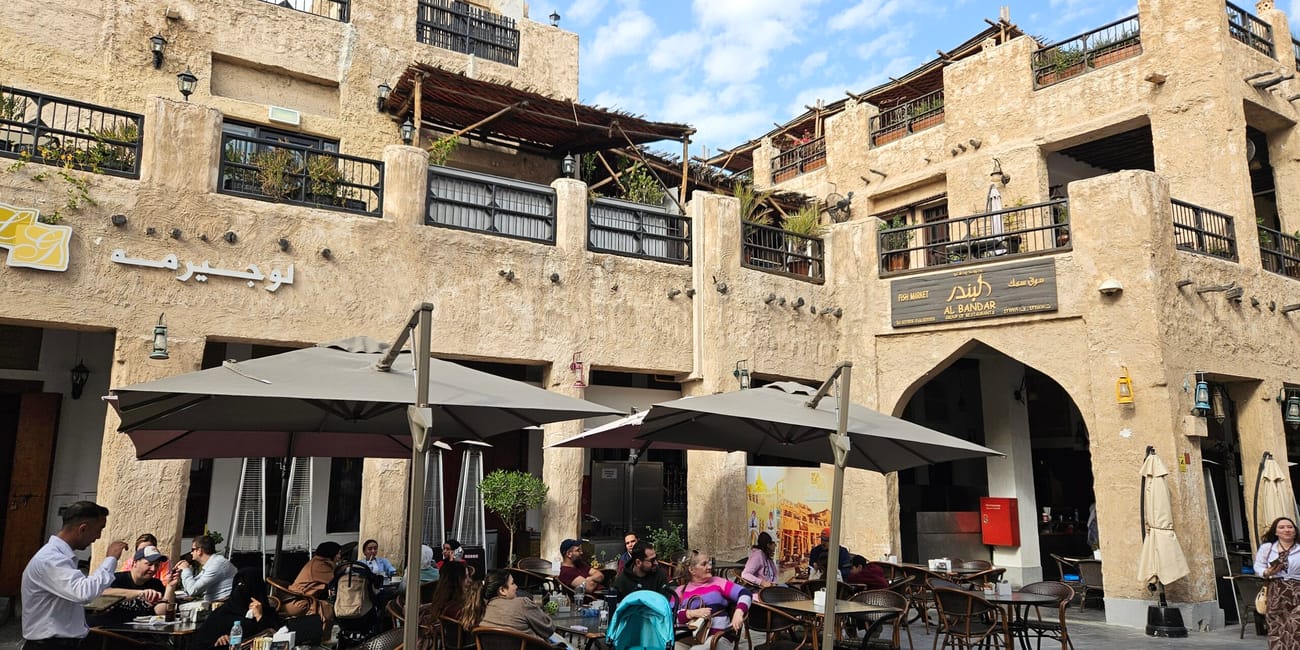 Souq waqif w doha z kawiarniami i tarasami pod parasolami na dziedzińcu.