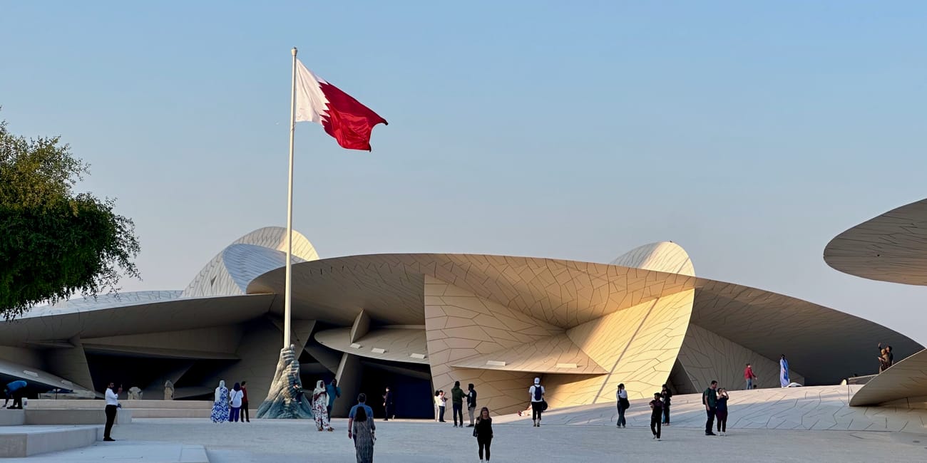 Muzeum narodowe w doha z flagą kataru i zwiedzającymi na placu