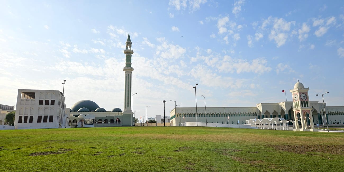 Souq waqif park w dosze z minaretem, zielonym trawnikiem i budynkami pod błękitnym niebem