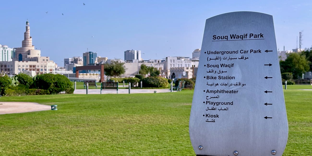 Souq waqif park w dosze z tablicą kierunkową i panoramą miasta w tle